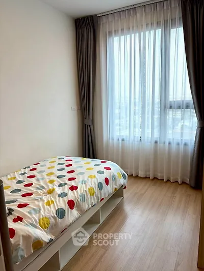 Cozy bedroom with colorful bedding and large window for natural light.