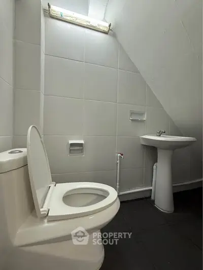 Compact bathroom with modern fixtures and sleek white tiles, ideal for efficient space utilization.