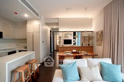 Modern open-plan living room with stylish kitchen and dining area, featuring elegant lighting and cozy decor.