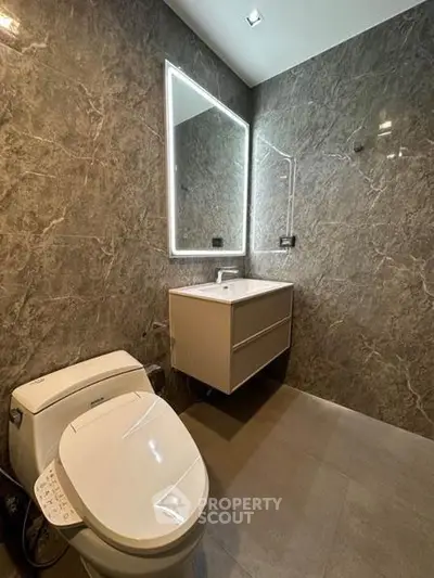 Luxurious modern bathroom with sleek marble walls and illuminated mirror