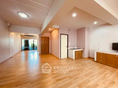 Spacious open-plan living room with wooden flooring and modern lighting