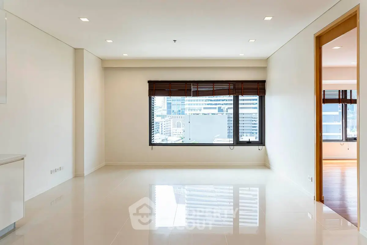 Spacious modern living room with large window and city view, perfect for urban living.