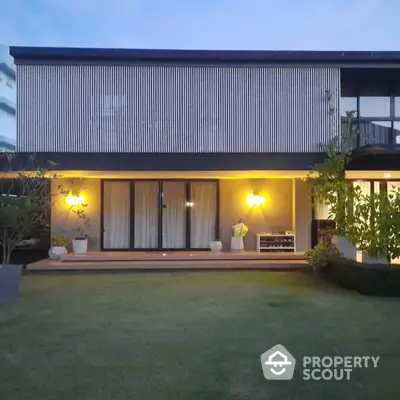 Modern two-story house with illuminated facade and spacious lawn