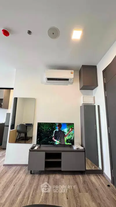 Modern living room with sleek furniture and wall-mounted TV, featuring air conditioning and stylish decor.