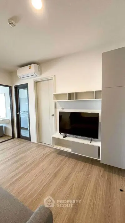 Modern living room with sleek TV unit and wooden flooring in a stylish apartment.