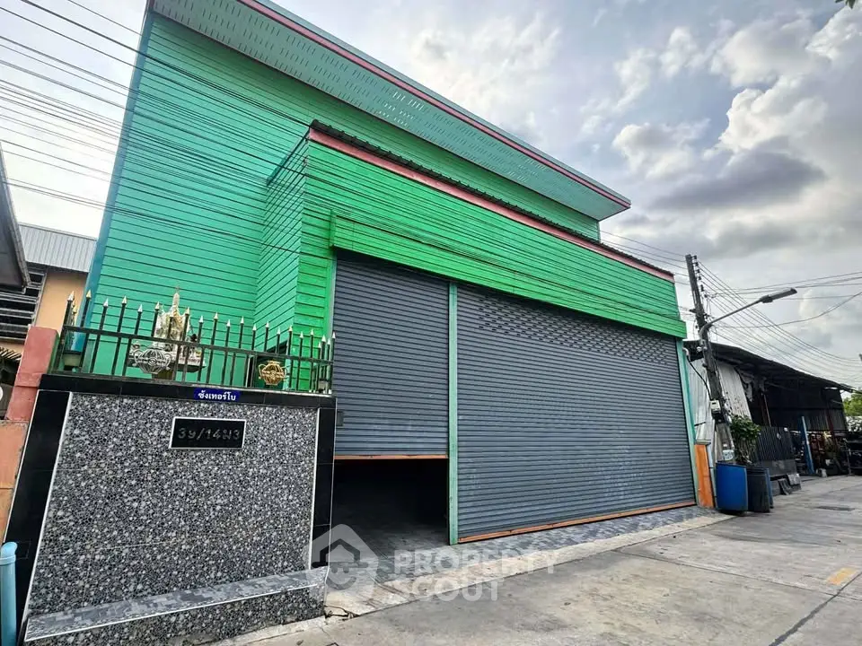 Spacious green industrial warehouse with large roller doors and modern exterior design.