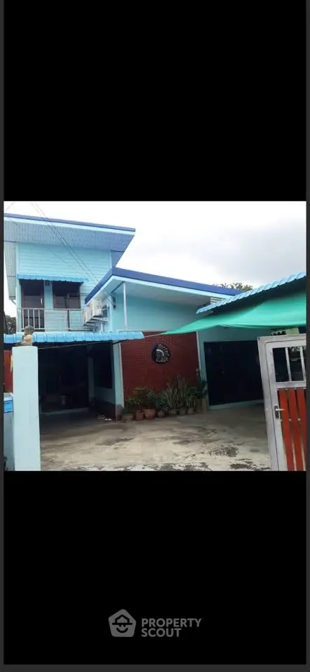 Charming two-story blue house with spacious driveway and lush garden.