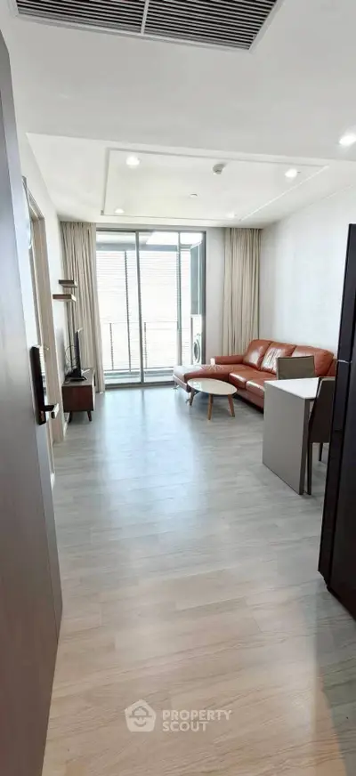 Modern living room with stylish leather sofa and large windows offering natural light.