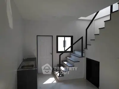 Modern minimalist interior with sleek staircase and compact kitchenette