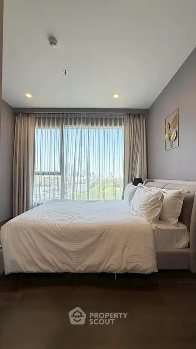 Luxurious bedroom with large windows offering stunning city views, elegant decor, and cozy ambiance.