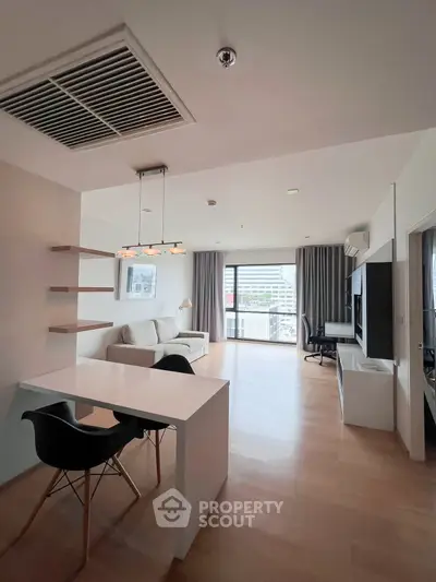 Modern open-plan living room with stylish furniture and large windows offering city views.