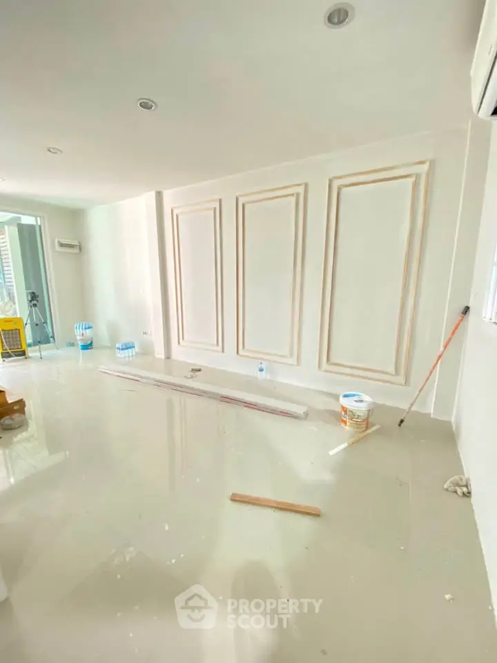 Spacious under-construction living room with elegant wall paneling and glossy tiled flooring.