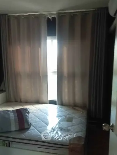Cozy bedroom with natural light filtering through curtains, featuring a comfortable bed and minimalist decor.