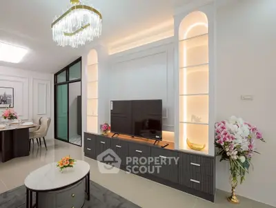 Elegant living room with modern decor, built-in shelves, and stylish chandelier