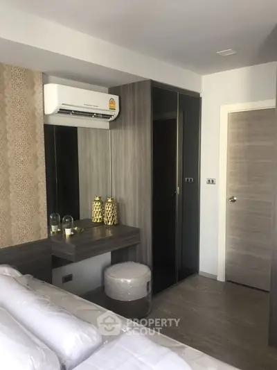 Modern bedroom with sleek design, featuring built-in wardrobe and air conditioning unit.
