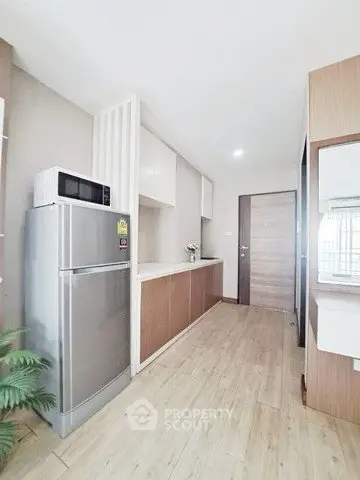 Modern kitchen with sleek appliances and wooden cabinetry in a stylish apartment.