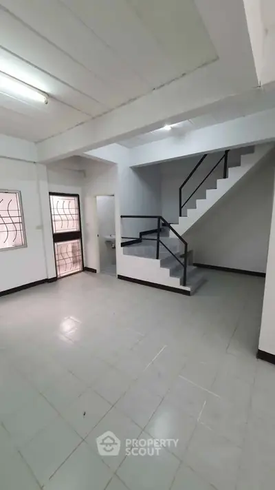 Spacious interior with modern staircase and large windows, perfect for natural light.