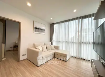 Modern living room with large windows and cozy beige sofa in a bright apartment.