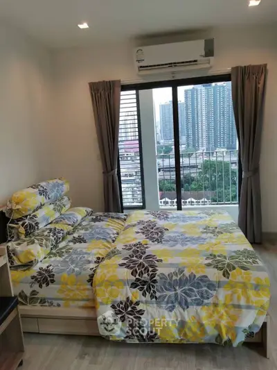 Cozy bedroom with floral bedding and city view from balcony in modern apartment.