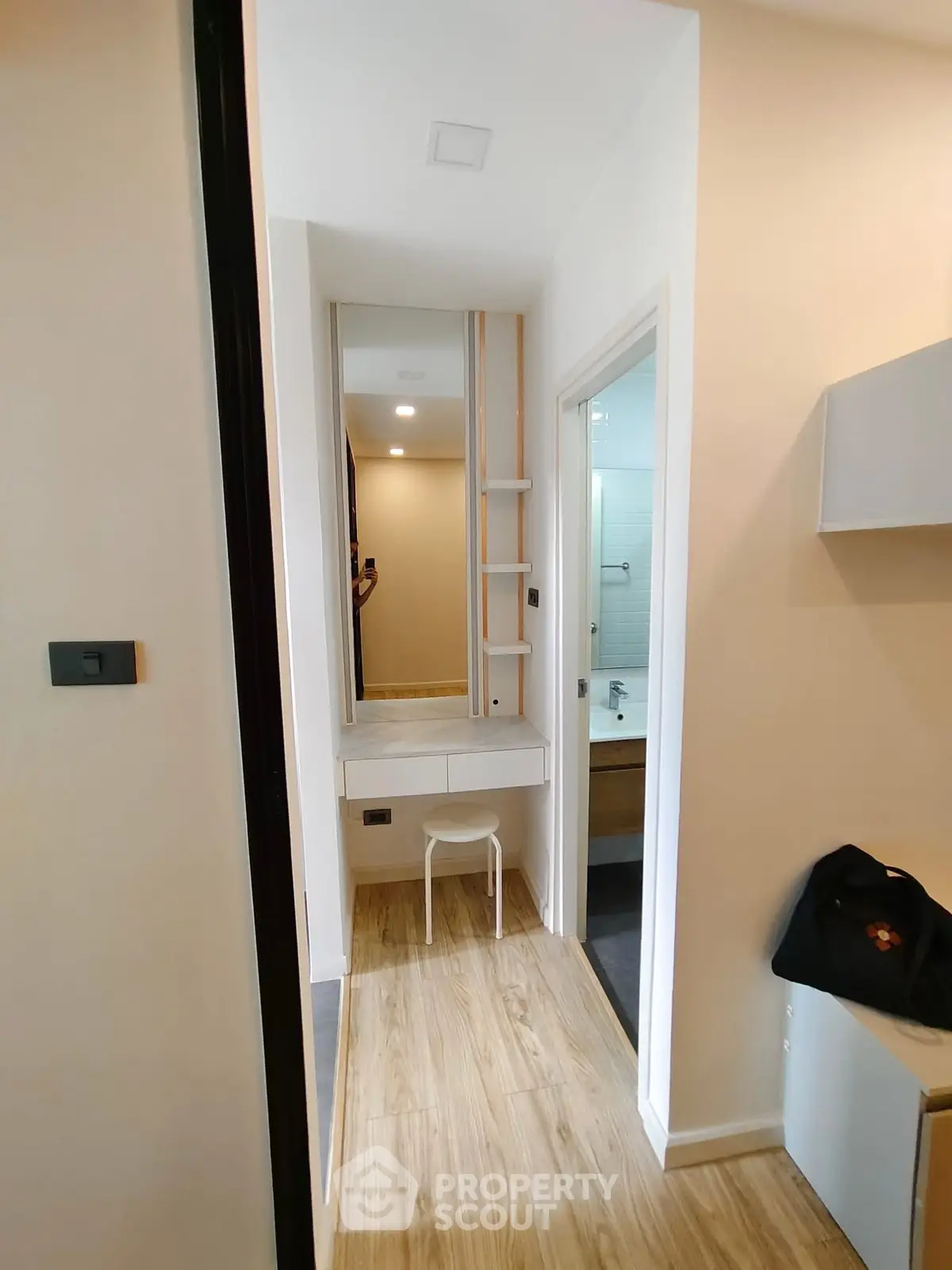 Modern hallway with wooden flooring leading to a bathroom and vanity area.