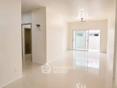 Spacious open-plan living area with glossy tiled floors and ample natural light.
