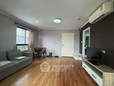 Spacious living room with modern decor and wooden flooring in a cozy apartment.