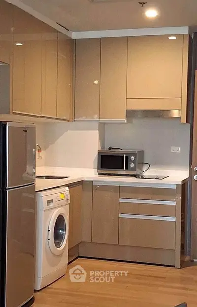 Modern kitchen with sleek cabinets, washing machine, and microwave in a compact layout.