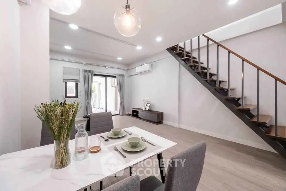 Modern open-plan living room with stylish staircase and dining area