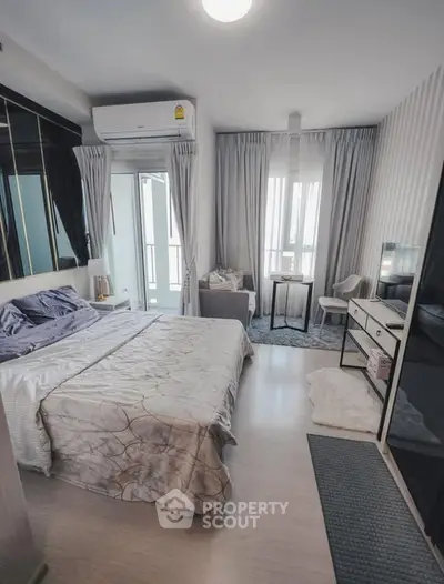 Modern bedroom with stylish decor and natural light, featuring a cozy seating area and sleek furnishings.