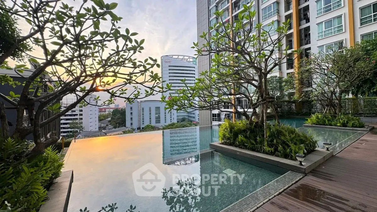 Luxurious rooftop pool with stunning city view at sunset, surrounded by lush greenery.