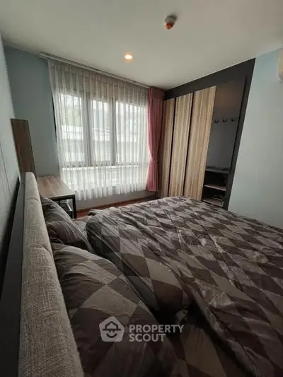 Cozy bedroom with large window and modern decor in a stylish apartment.