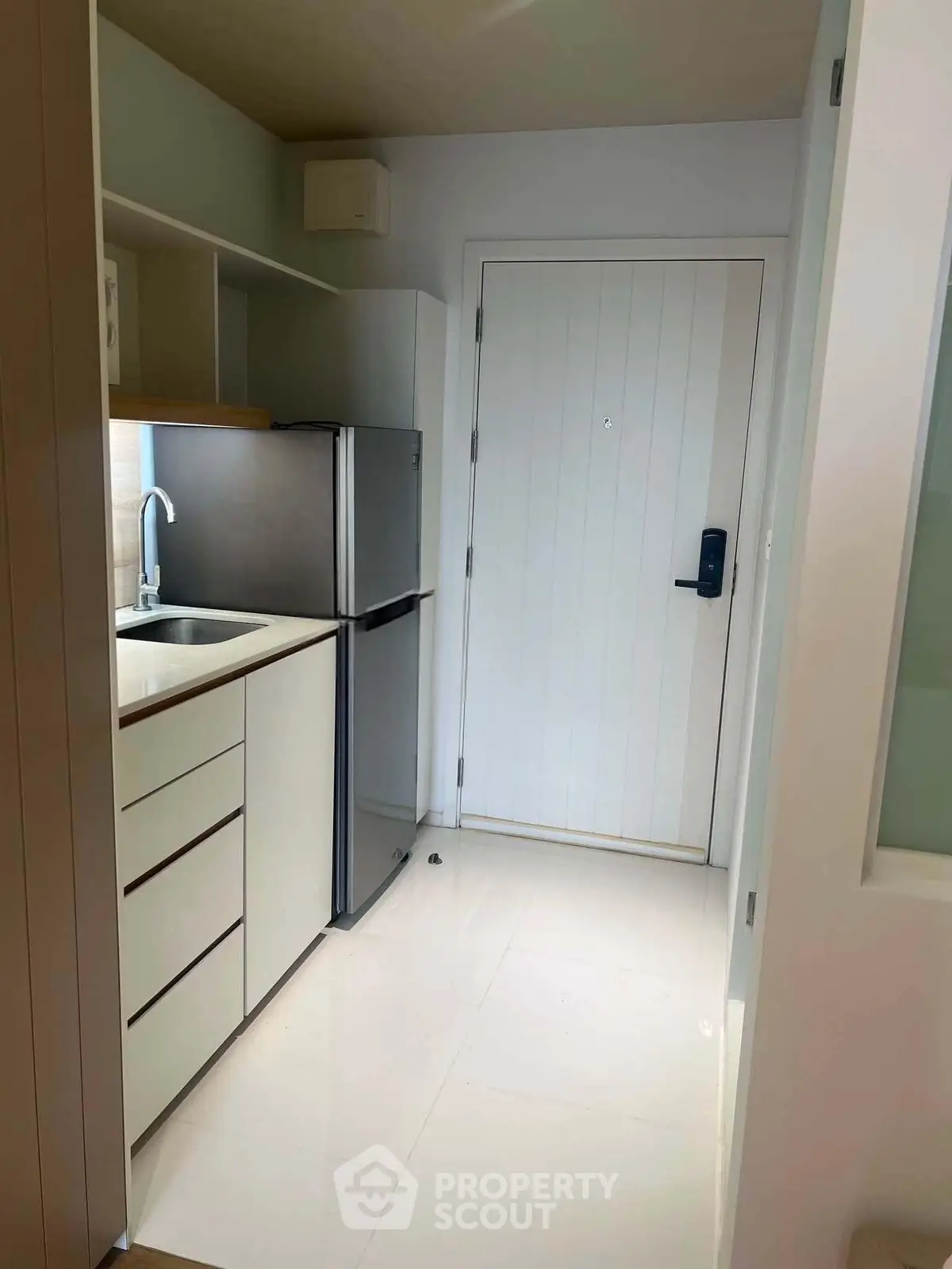 Compact modern kitchen with sleek cabinetry and stainless steel appliances in a cozy apartment.
