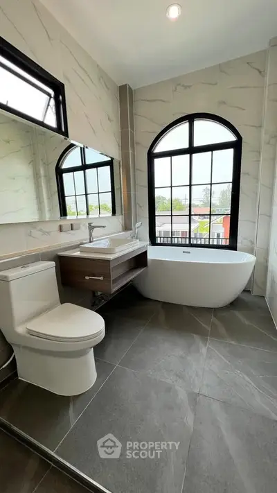 Luxurious bathroom with freestanding tub and large window view.