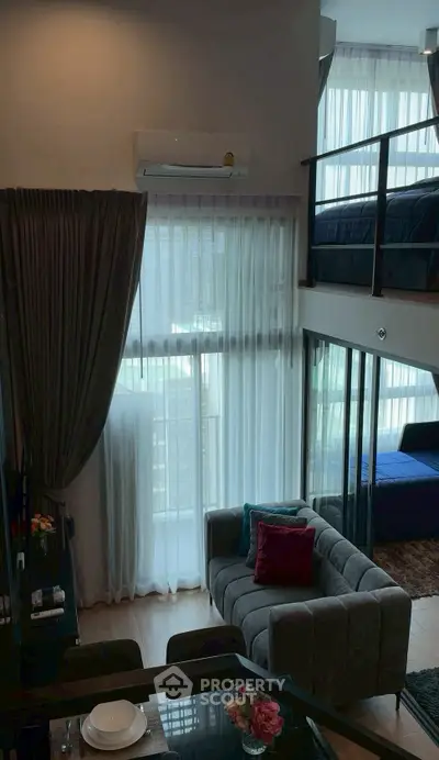 Modern loft apartment with high ceilings and large windows, featuring a cozy living area and stylish mezzanine bedroom.
