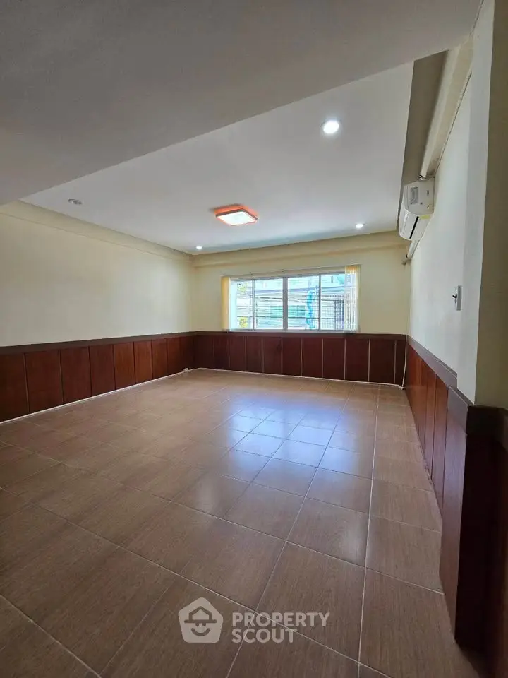 Spacious unfurnished room with tiled flooring and large window, perfect for customization.
