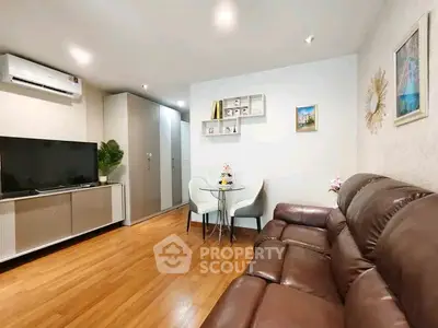 Modern living room with leather sofa, TV, and dining area in stylish apartment.