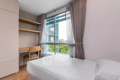 Bright and cozy bedroom with large window and built-in desk, perfect for a serene living experience.