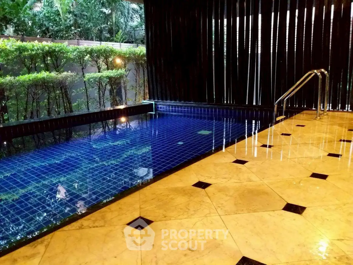 Luxurious indoor pool with elegant tile flooring and lush greenery view.