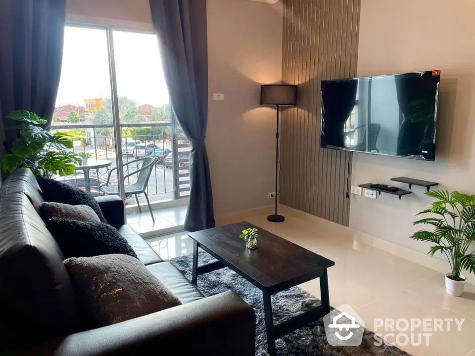 Modern living room with sleek black sofa, wall-mounted TV, and balcony view, perfect for urban living.