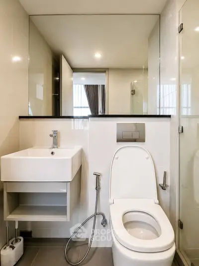 Modern bathroom with sleek fixtures and a spacious layout, featuring a contemporary toilet and sink.