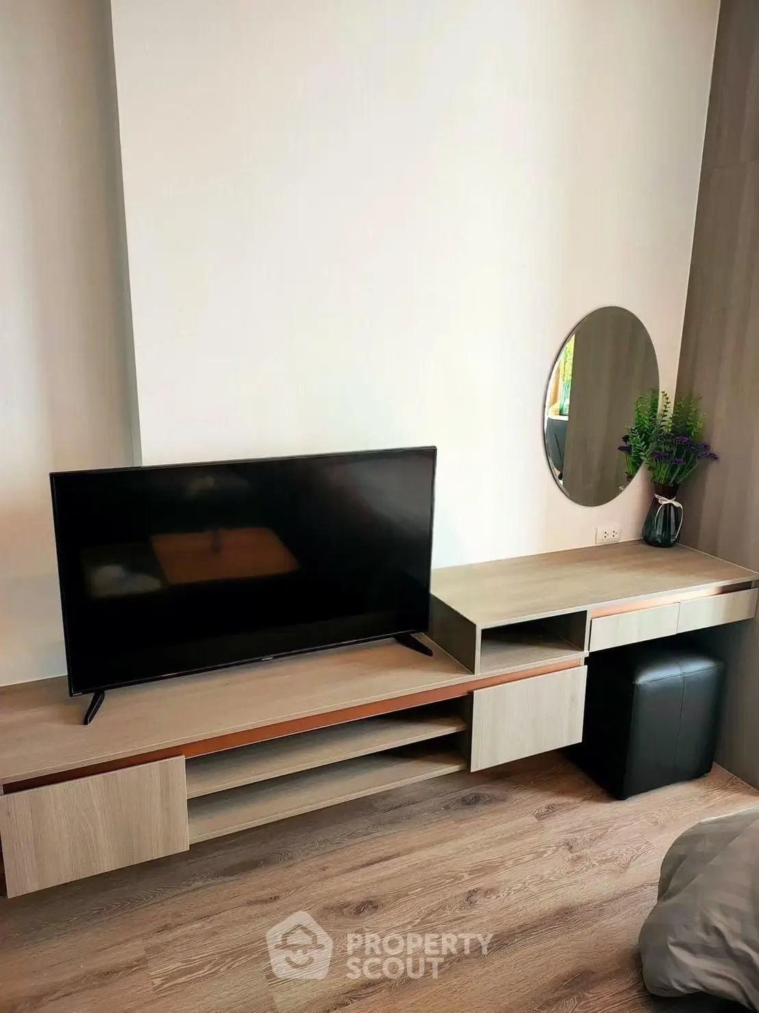 Modern living room with sleek TV stand and round mirror, perfect for stylish urban living.