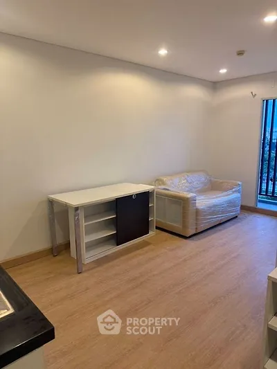 Modern living room with sleek flooring and cozy sofa, perfect for urban living.