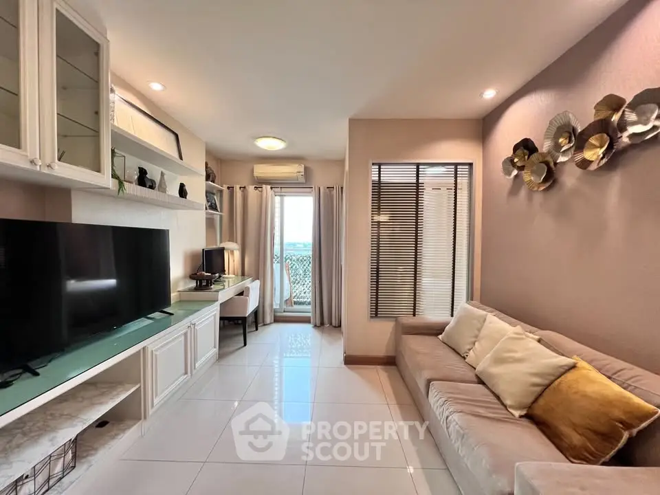 Modern living room with stylish decor and large TV, featuring a cozy sofa and elegant shelving.