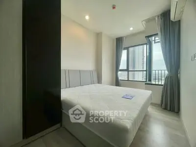 Modern bedroom with large window and city view in high-rise apartment