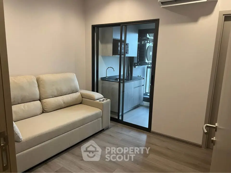 Modern living room with cozy sofa and view into sleek kitchen