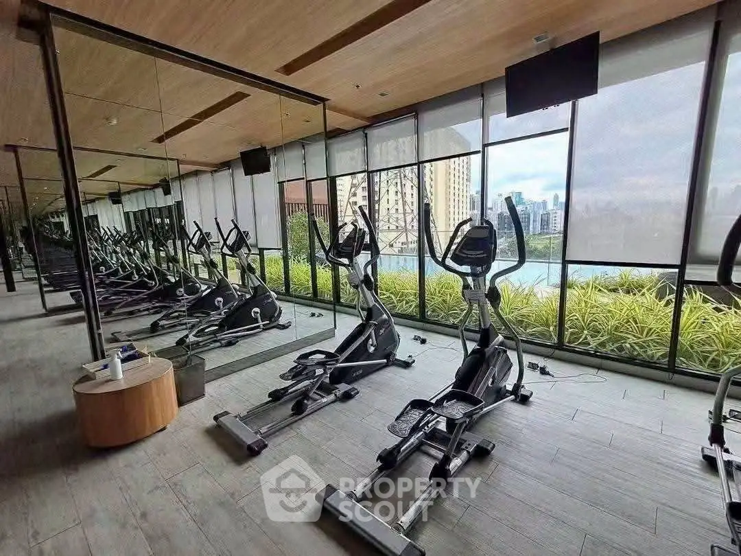 Modern gym with city view and state-of-the-art equipment in luxury residential building.