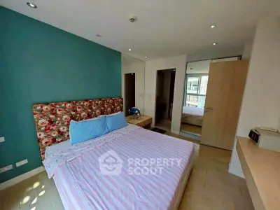 Cozy bedroom with floral headboard and teal accent wall in modern apartment