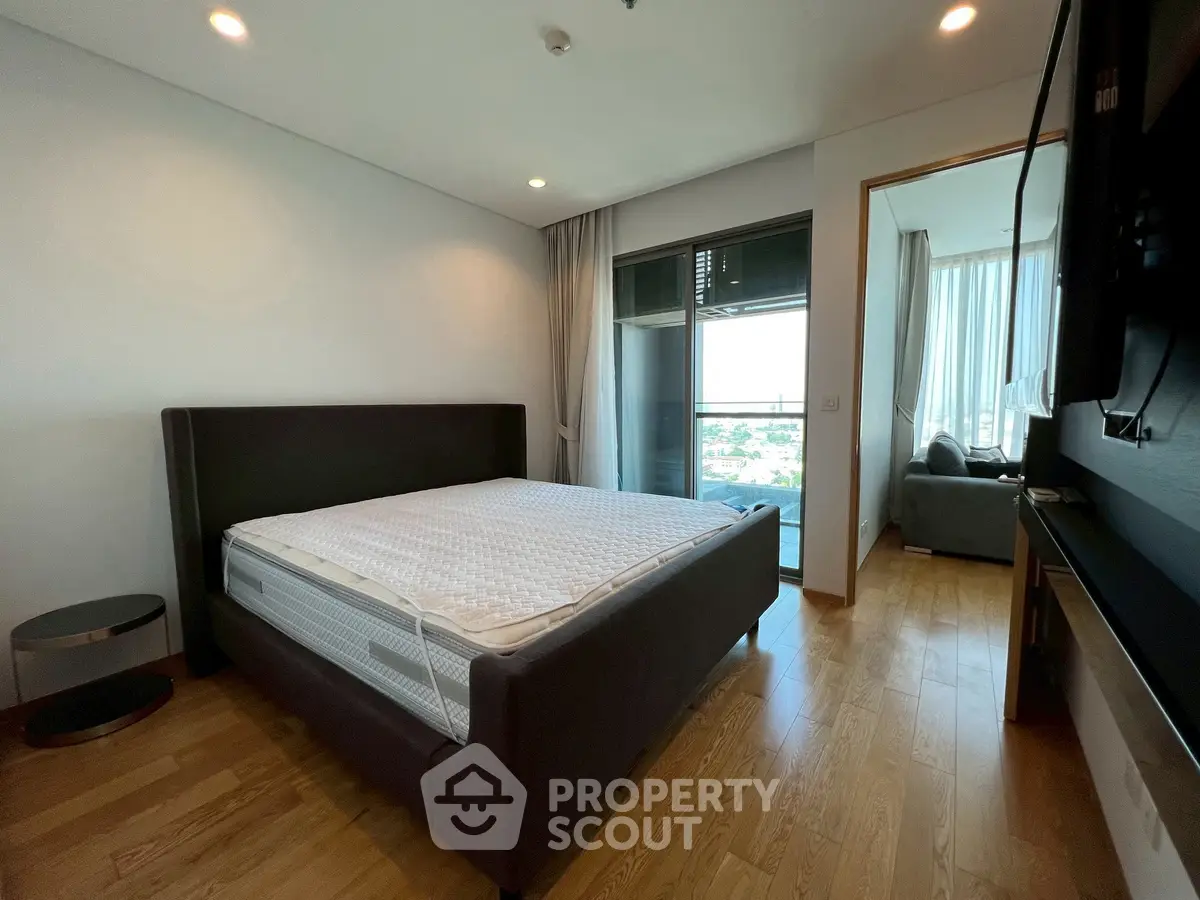 Spacious bedroom with modern design and balcony view in luxury apartment.