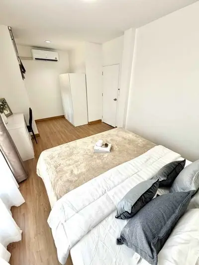 Modern bedroom with cozy bed, sleek wardrobe, and air conditioning in a bright apartment.