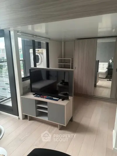 Modern living room with large windows and sleek furniture in a high-rise apartment.